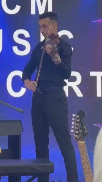 Karim playing solo violin on stage at a live event.